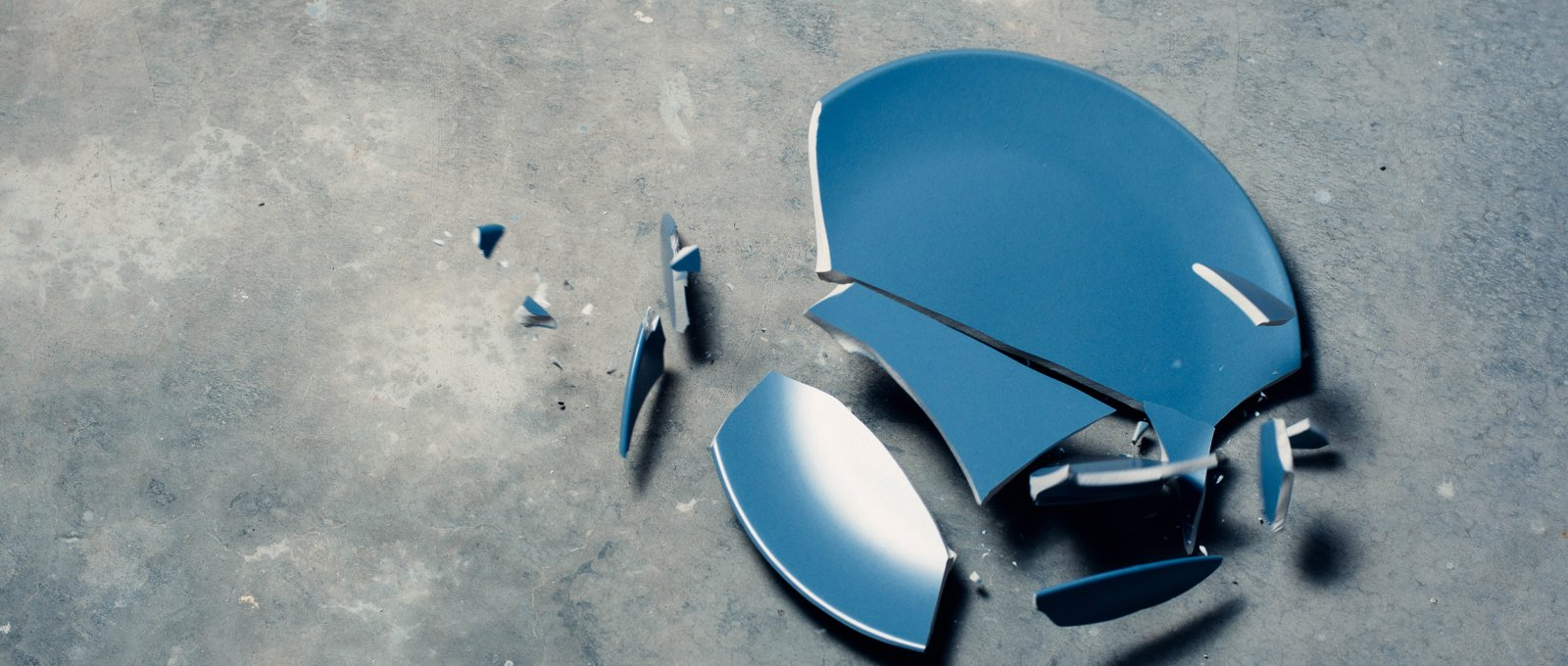 Blue ceramic plate broken on a grey concrete floor