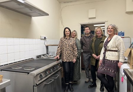 Photo of several people in the kitchen at the Salcare charity looking at the newly-installed cooker