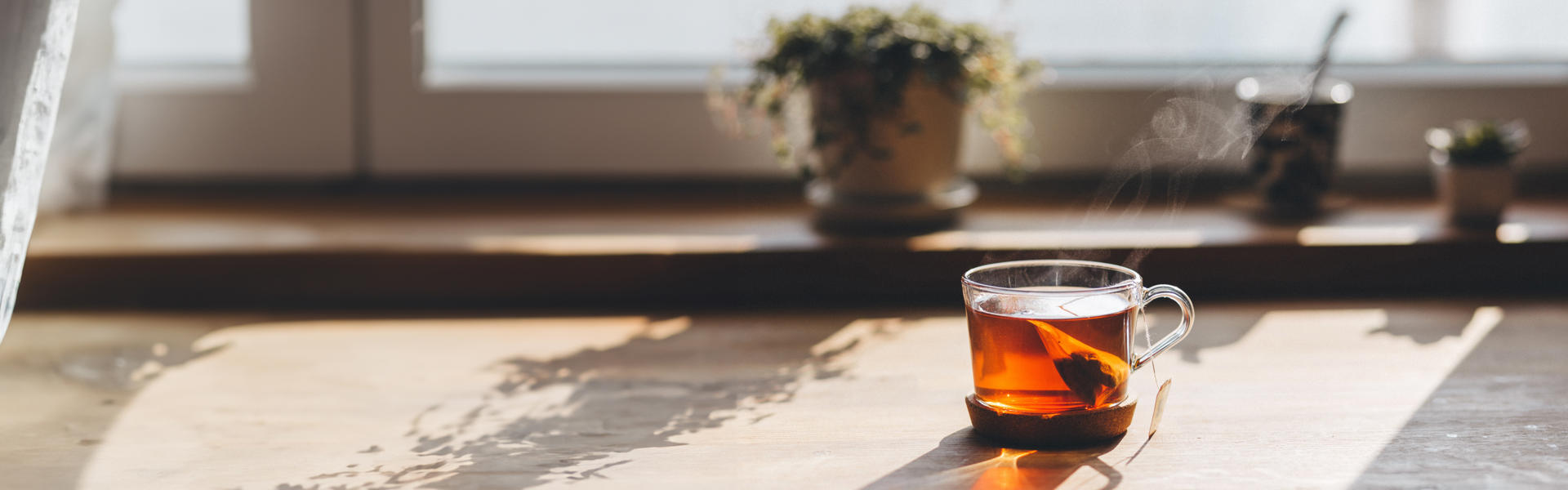 A cup of tea in a glass mug sitting in autumn sunshine