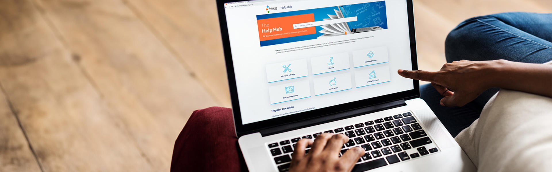 Photo of someone sat down using a laptop with The Help Hub on screen