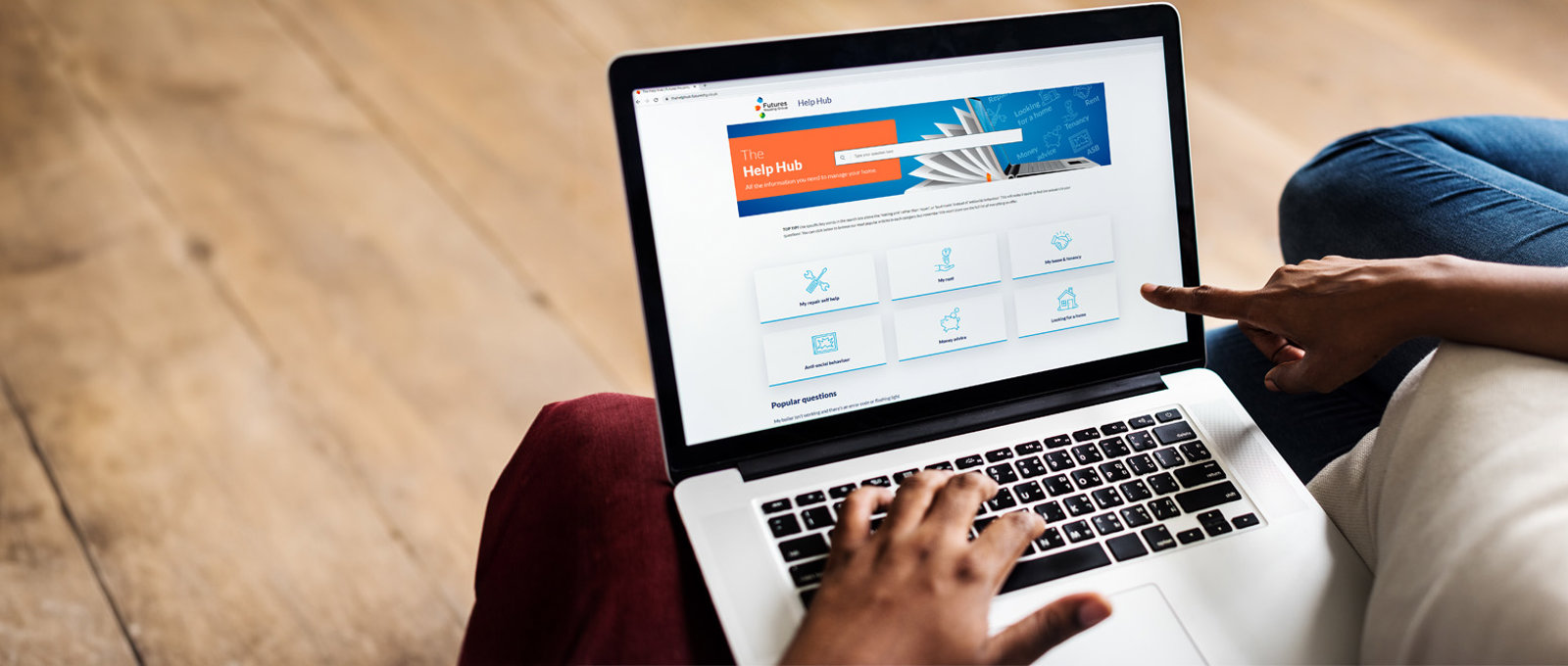 Photo of someone sat down using a laptop with The Help Hub on screen