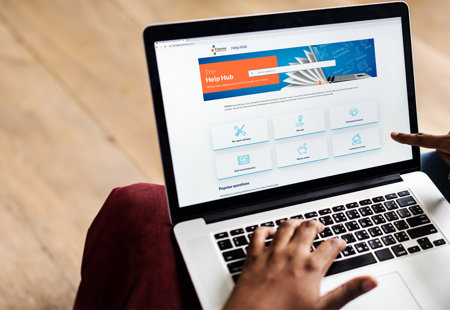 Photo of someone sat down using a laptop with The Help Hub on screen