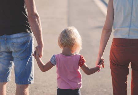 Little girl holding hands in the middle of two adults