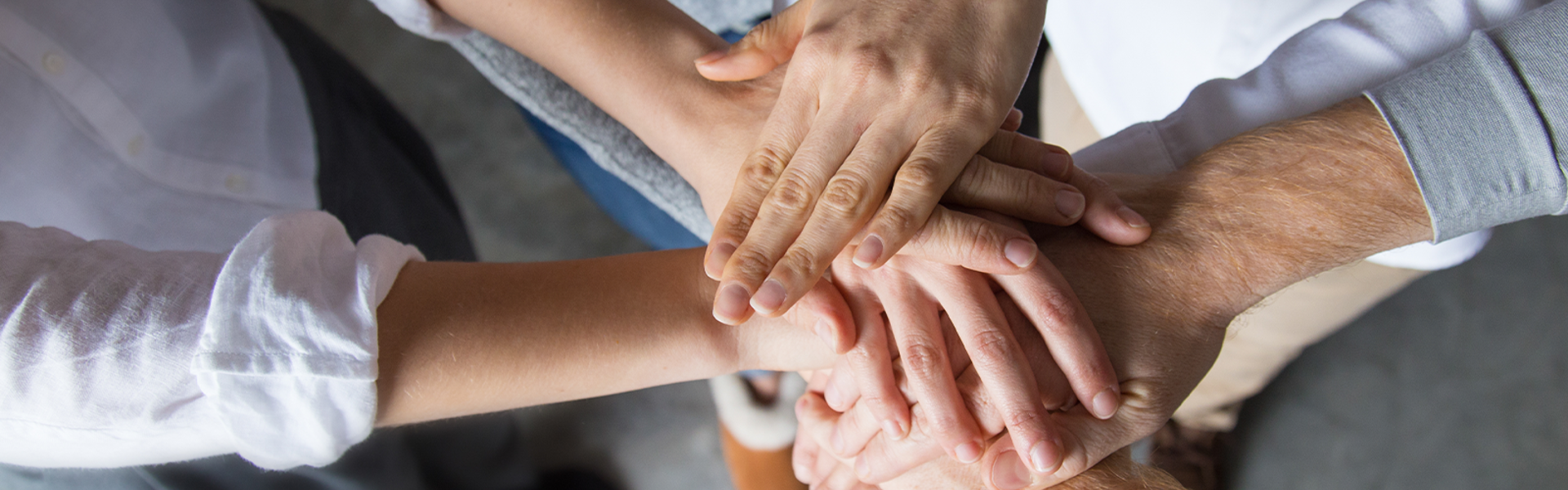 Close-up photo of a group of hands in a circle on top of each other