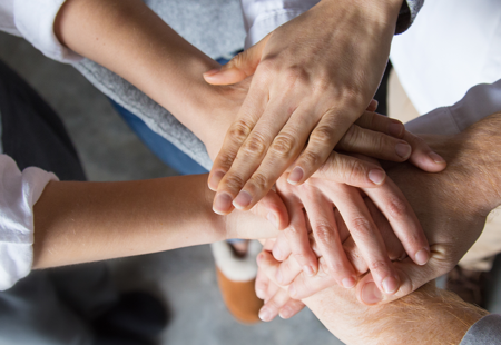 Close-up photo of a group of hands in a circle on top of each other
