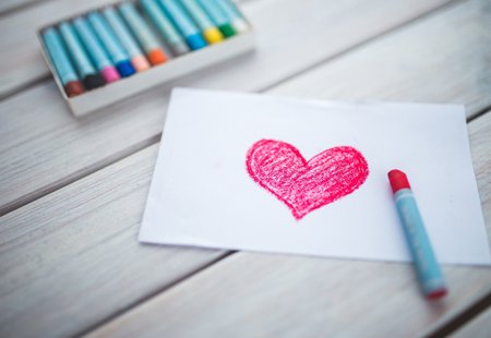 A red heart drawn in crayon on a white piece of paper