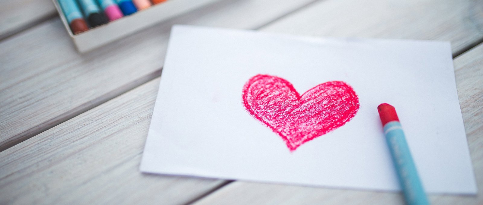 A red heart drawn in crayon on a white piece of paper