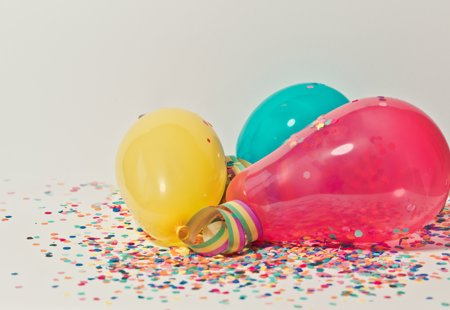 Yellow, teal and pink balloons against a confetti background.