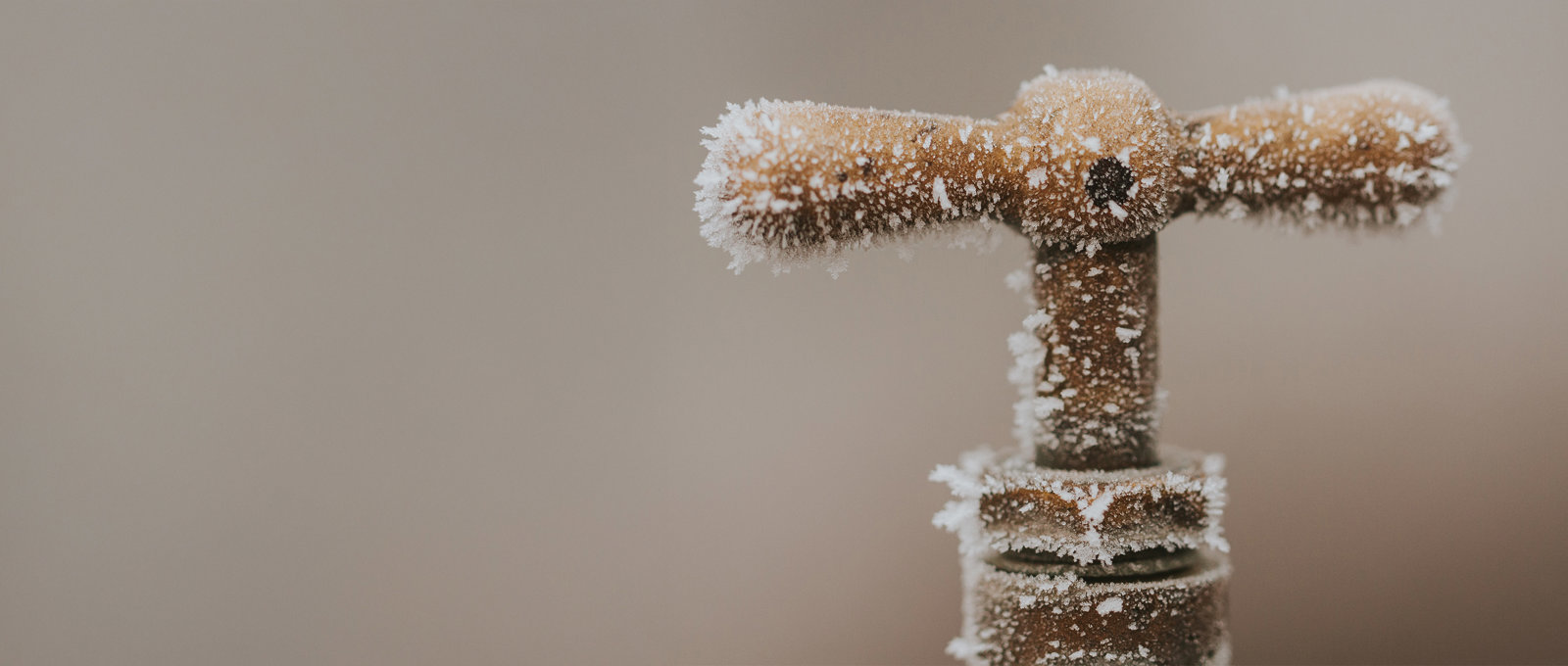Close up photo of a copper tap handle covered in frost and ice crystals