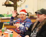 Photo of a man wearing a santa hat sat at a table with Christmas decorations on