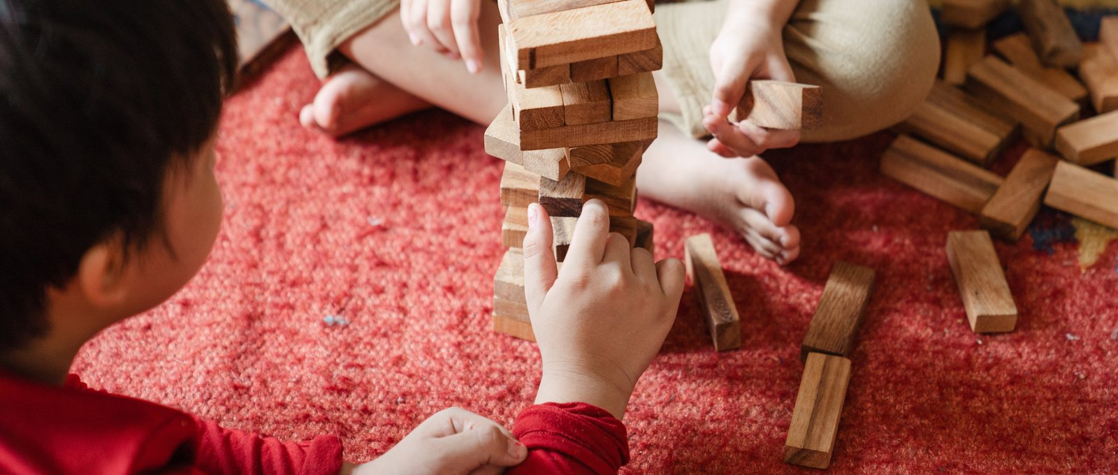 Photograph of two children sitting on the floor playing the game Jenga