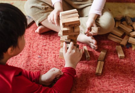 Photograph of two children sitting on the floor playing the game Jenga