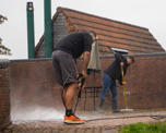 Colleagues jet-washing a patio