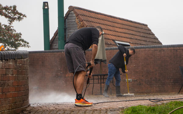 Colleagues jet-washing a patio