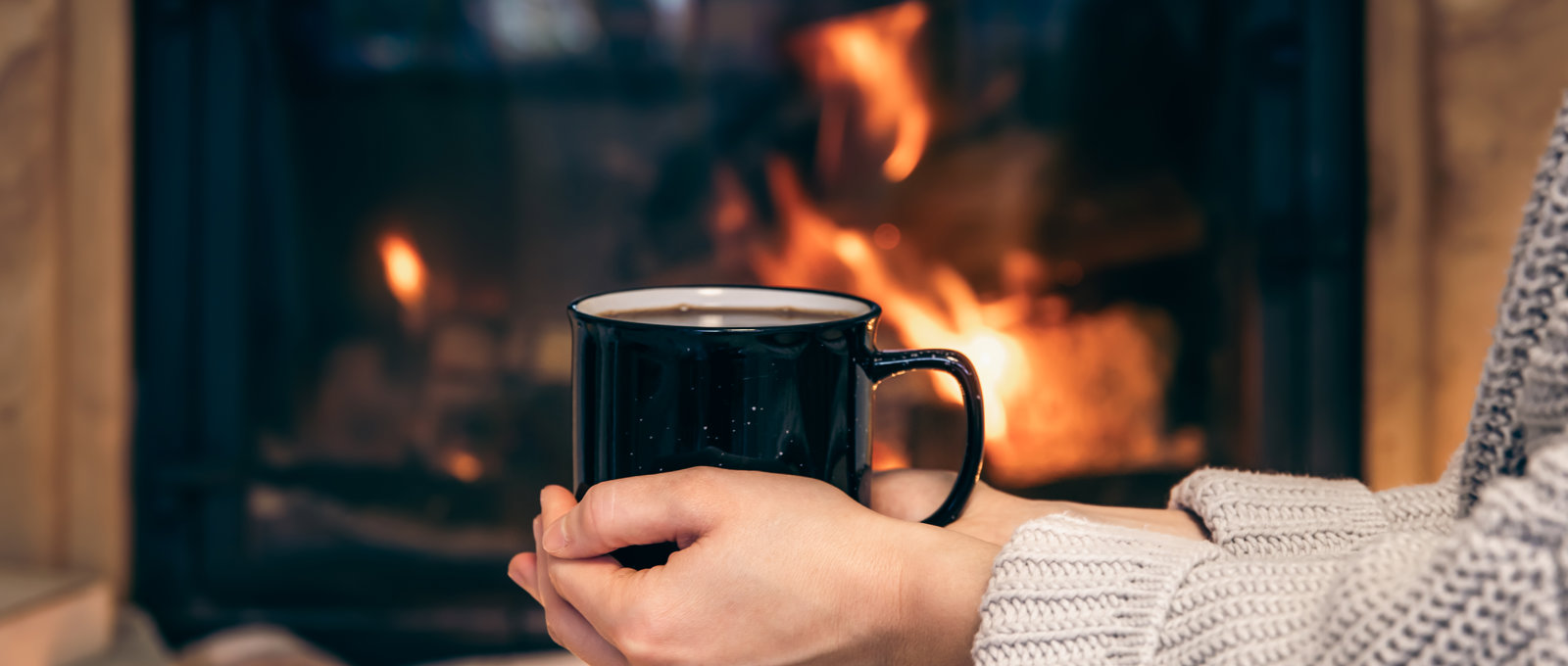 Cup With Hot Drink Female Hands Blurred Fireplace Background