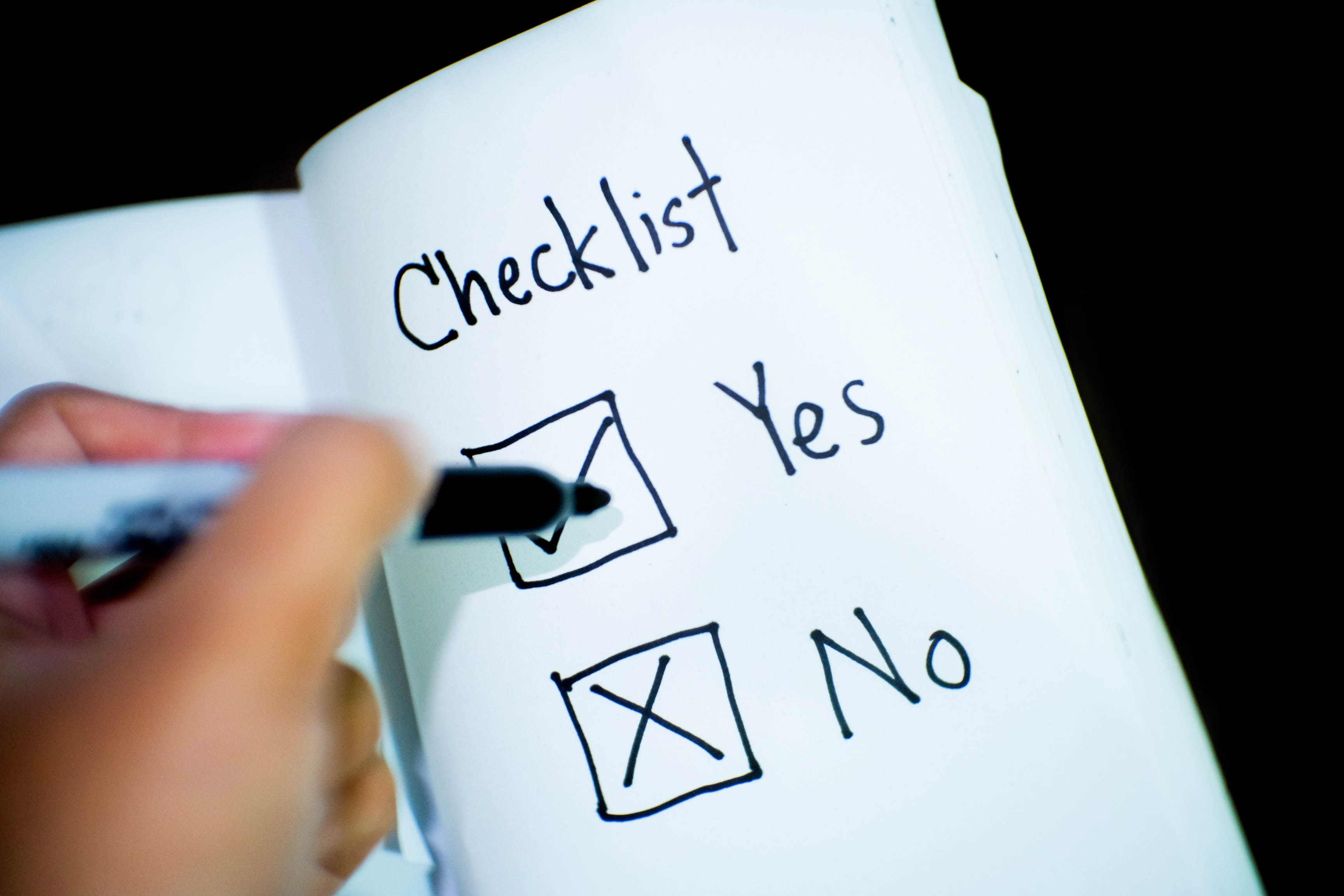 close-up photo of someone about to tick one of two boxes in a notebook marked 'yes' and 'no'