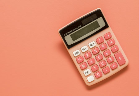 Photograph of a salmon-coloured calculator on a salmon-coloured background