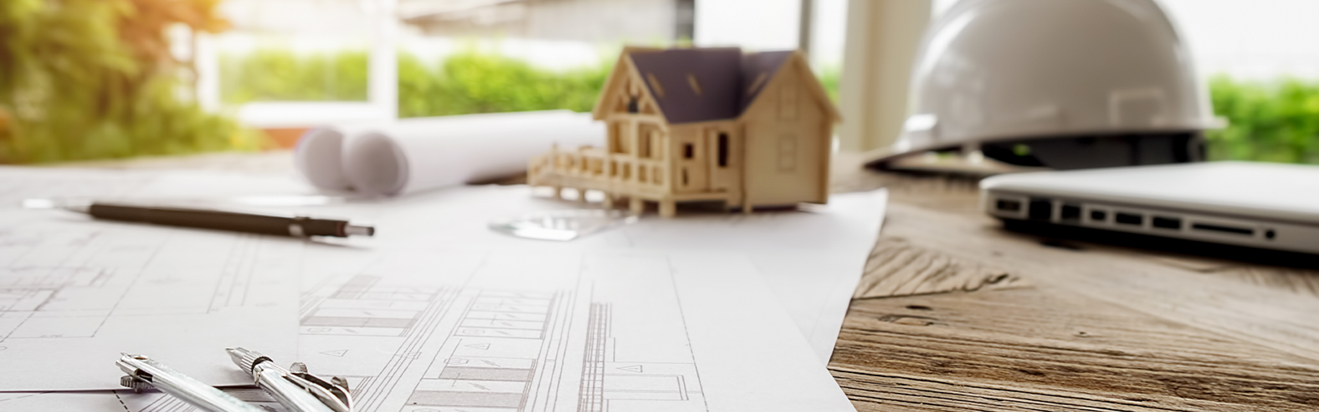 Photo of a small wooden model house on top of a table with sheets of paper