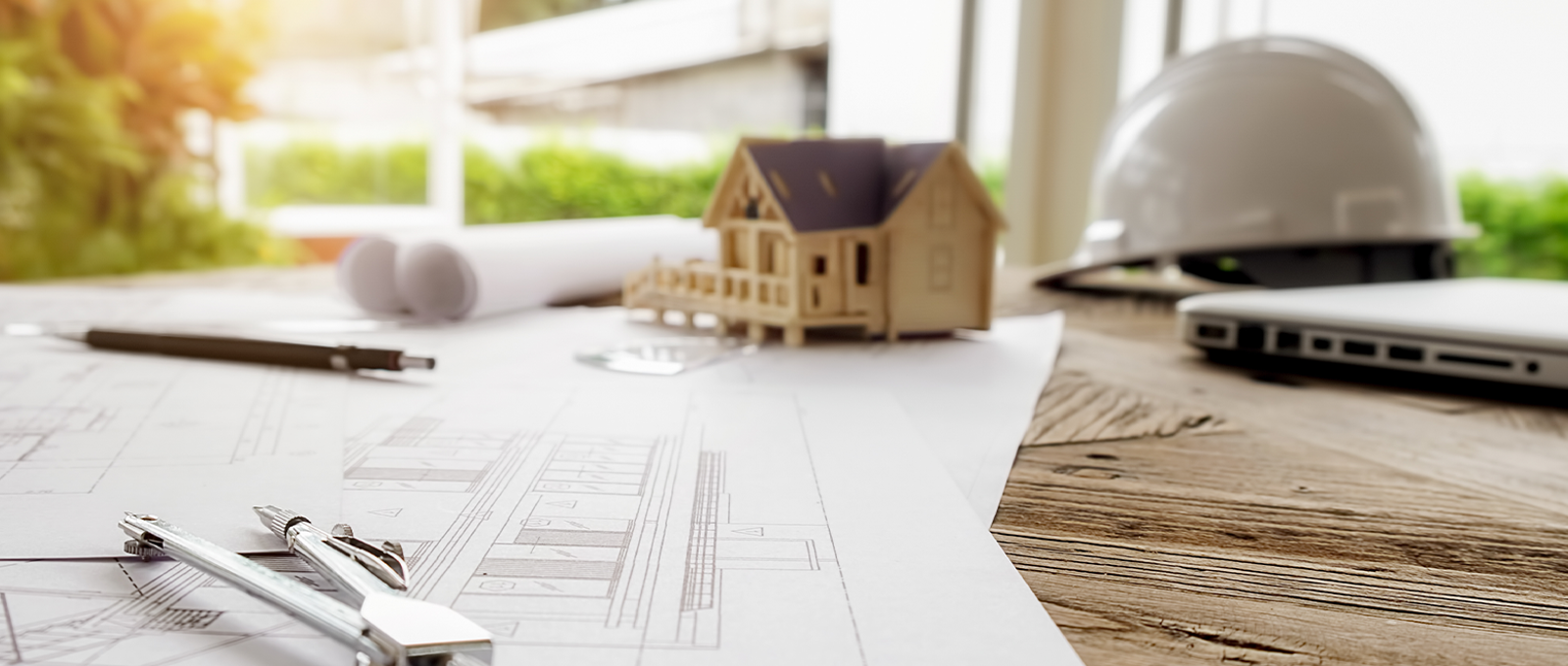 Photo of a small wooden model house on top of a table with sheets of paper