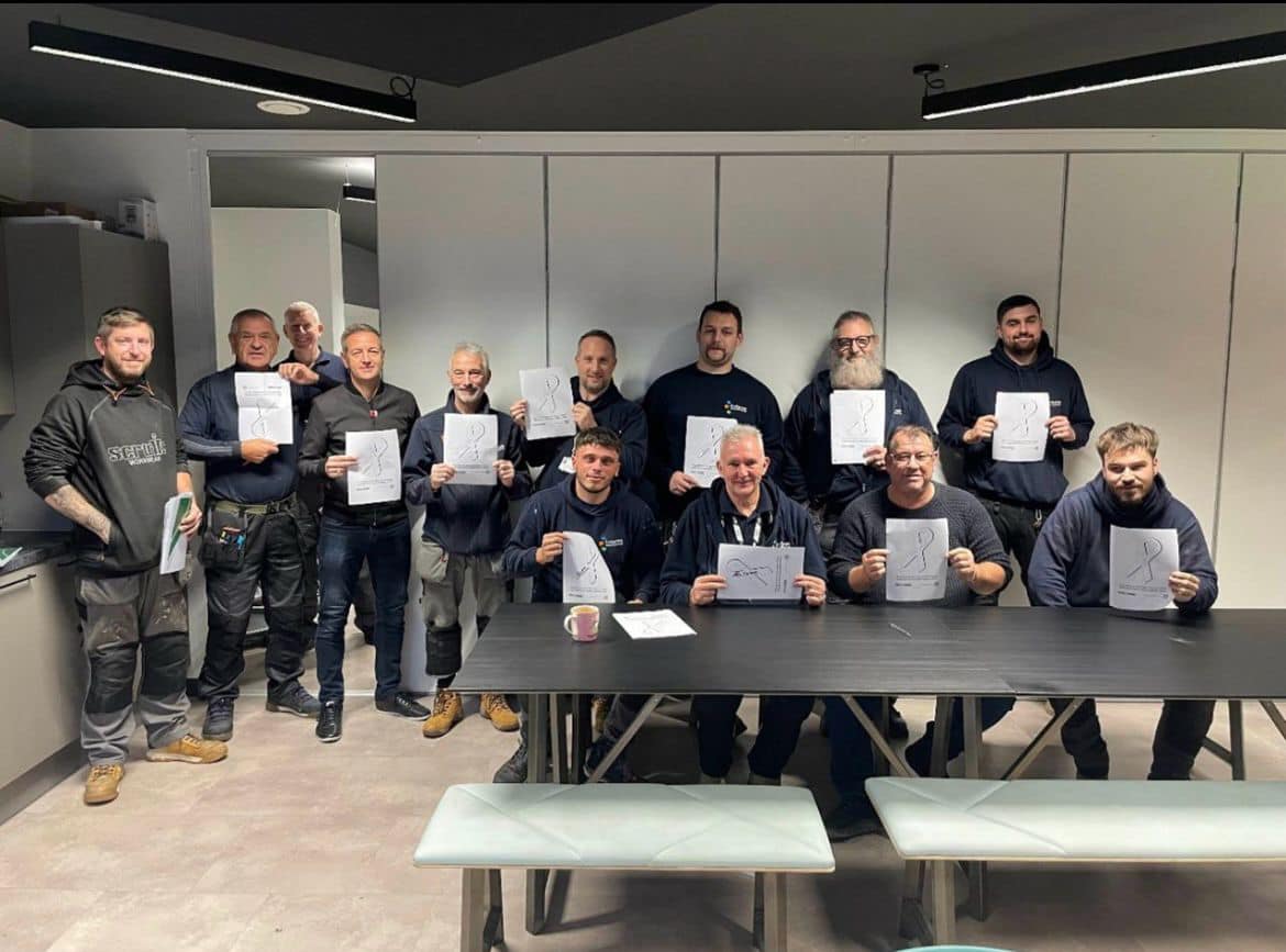 Photo of a group of people holding a piece of paper for White Ribbon Day