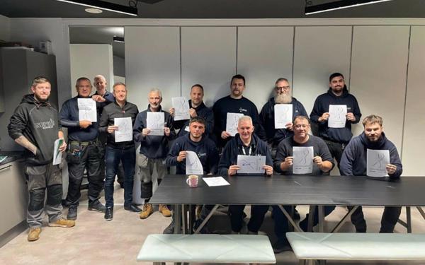 Photo of a group of people holding a piece of paper for White Ribbon Day