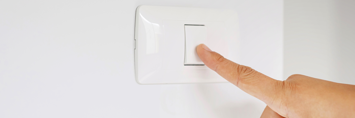 A person switching off a light switch