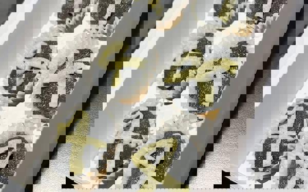 Photo of a box of cupcakes with a white ribbon iced on