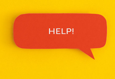 A photo of a red speech bubble against a yellow background' The word 'Help!' is written in upper case in white text inside the speech bubble.