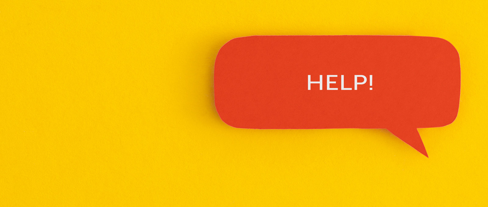 A photo of a red speech bubble against a yellow background' The word 'Help!' is written in upper case in white text inside the speech bubble.