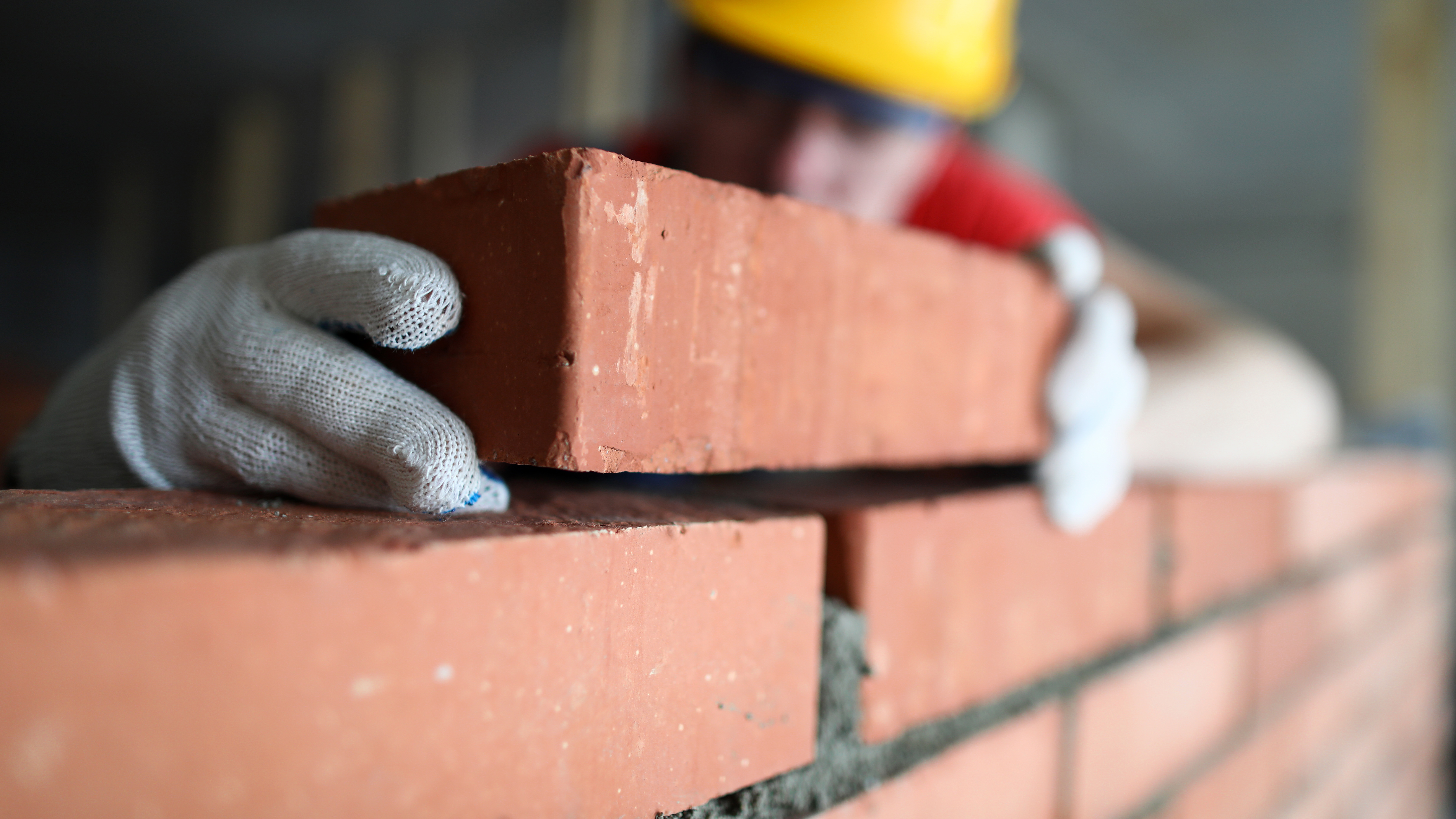 close up photo of a brick being added to a wall