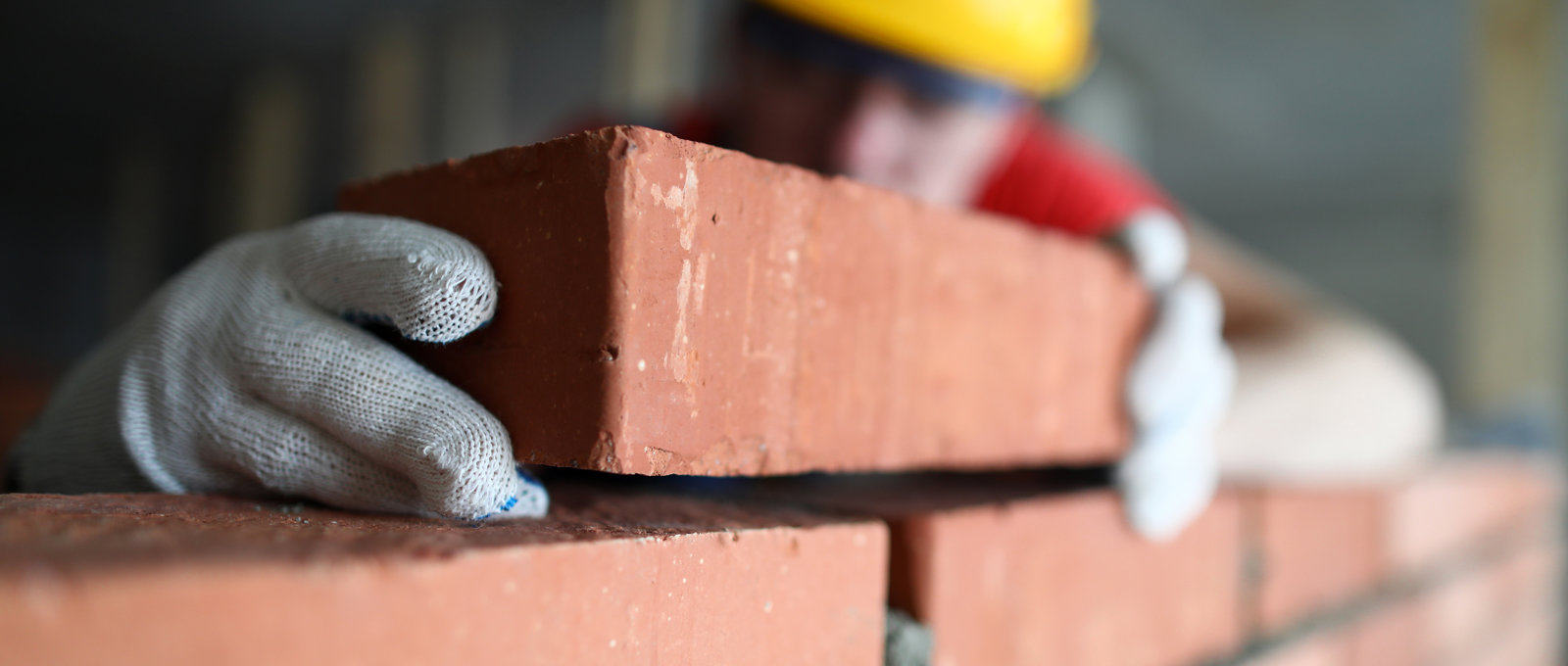 close up photo of a brick being added to a wall