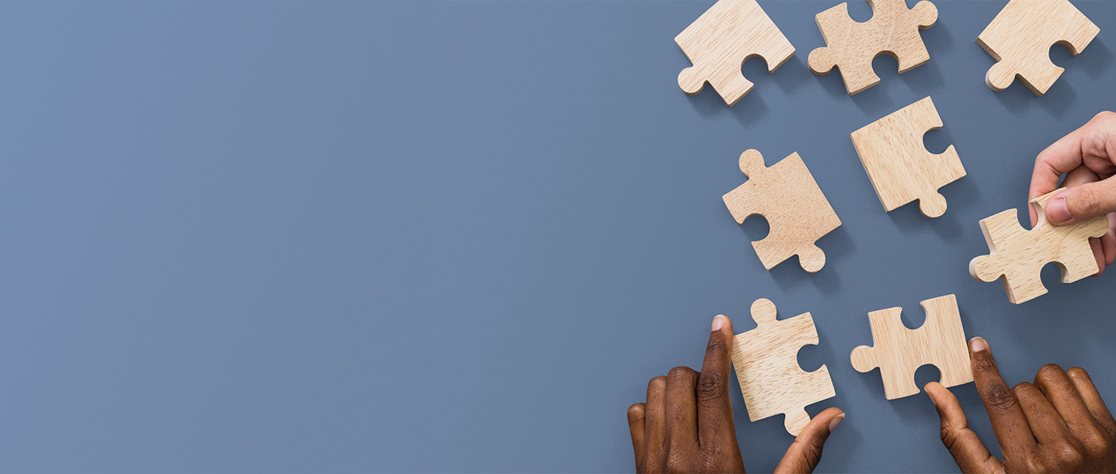 Wooden Puzzle Pieces With Hands Holding Some Of The Pieces