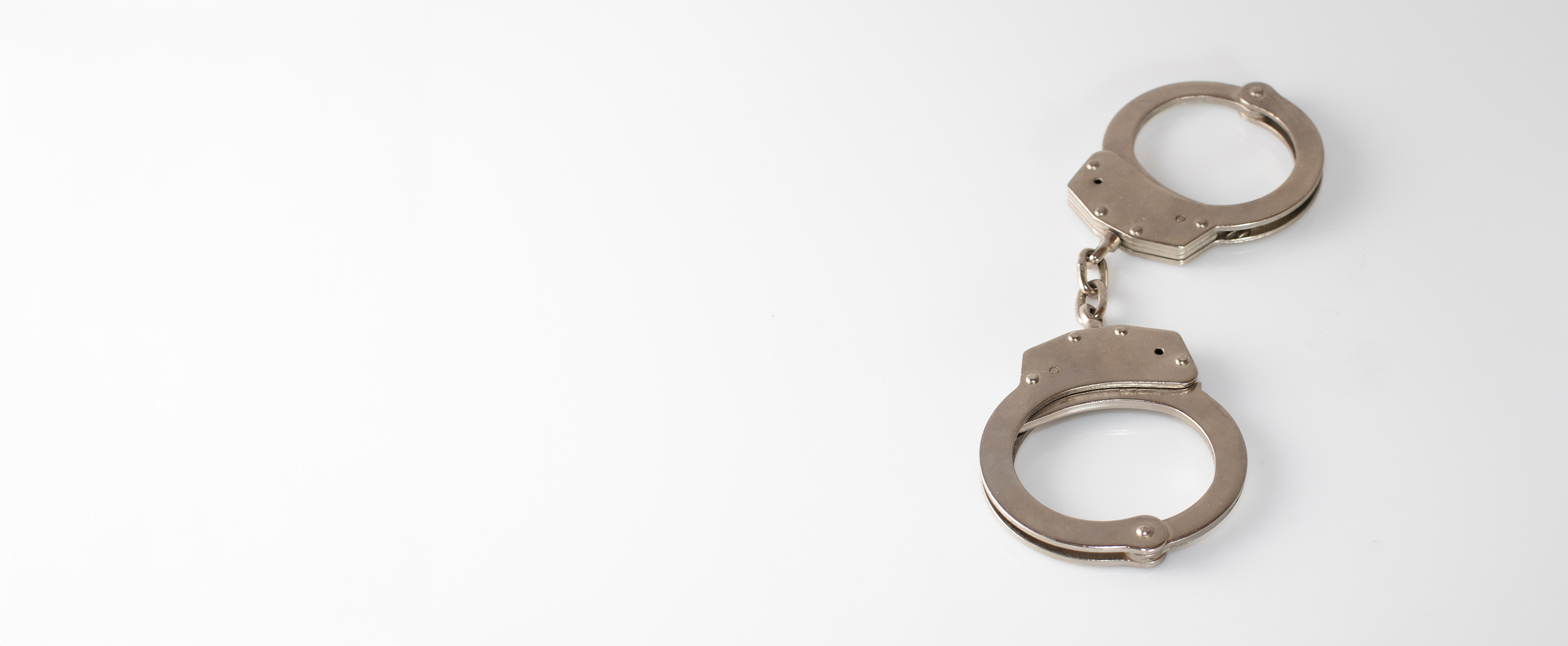 Close-up photo of some metal handcuffs on a white background