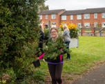 Colleague holding several plants in hand while walking outside