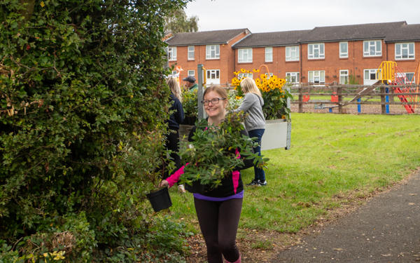 Colleague holding several plants in hand while walking outside