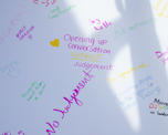 A close up of our pride graffiti wall reading "opening up conversation without judgement" in bright purple handwriting