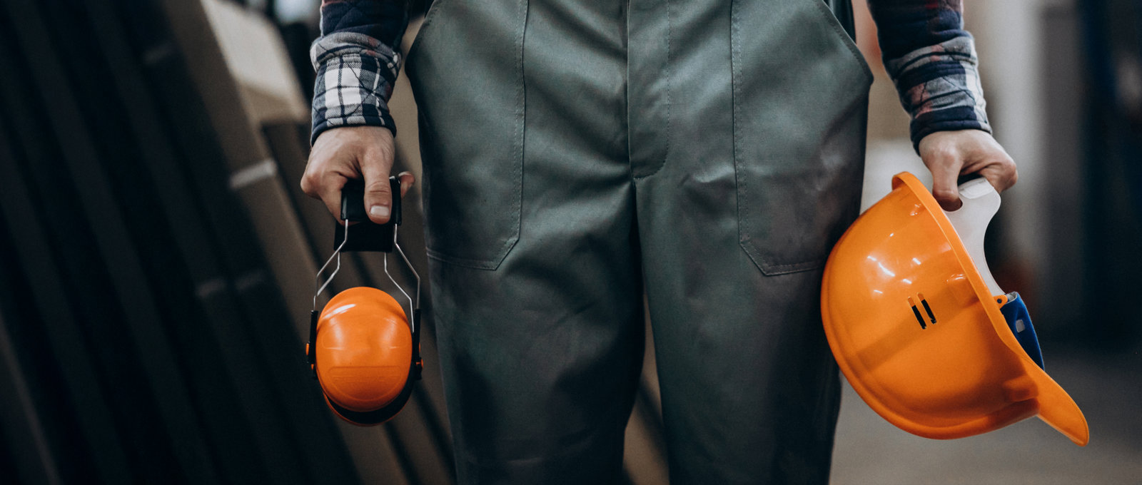 Construction worker holding safety earphones and helmet