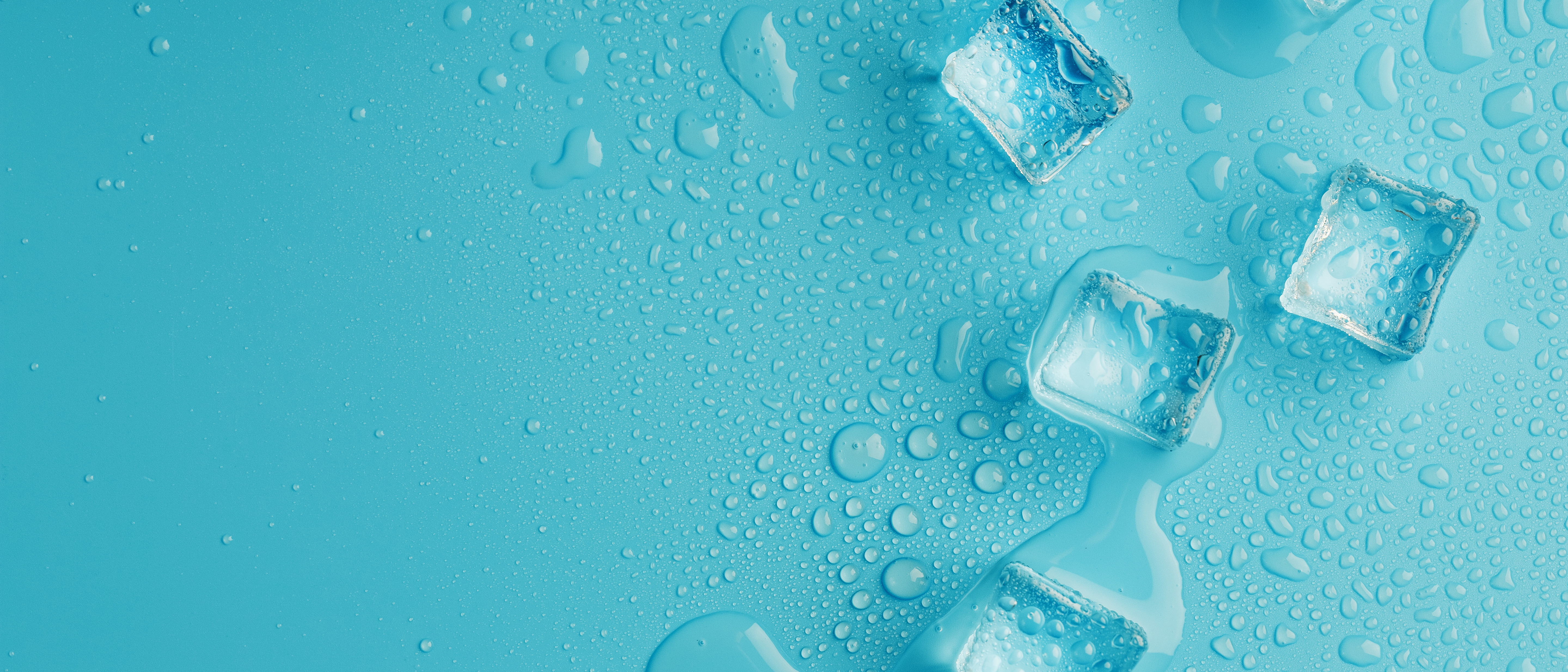 Close-up photo of ice cubes scattered on a light blue surface