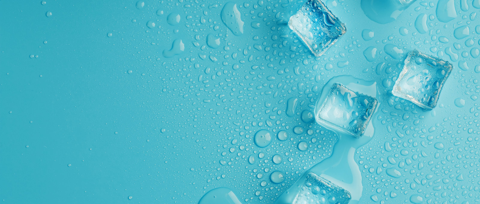 Close-up photo of ice cubes scattered on a light blue surface