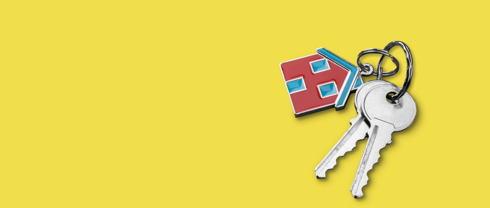 Photograph of two keys attached to a house-shaped keyring, lying on a yellow surface