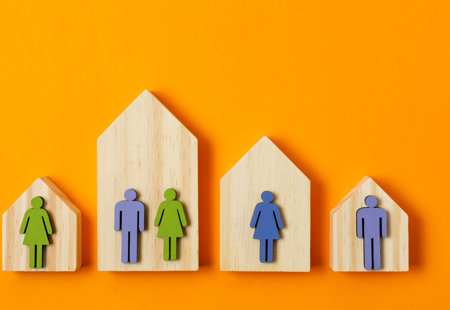 photo of four wooden house shapes on an orange surface. Each house also has one or two wooden cut-out people shapes overlaid