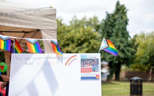 A canvas reading 'how can your community feel more inclusive', surrounded by Pride flags 