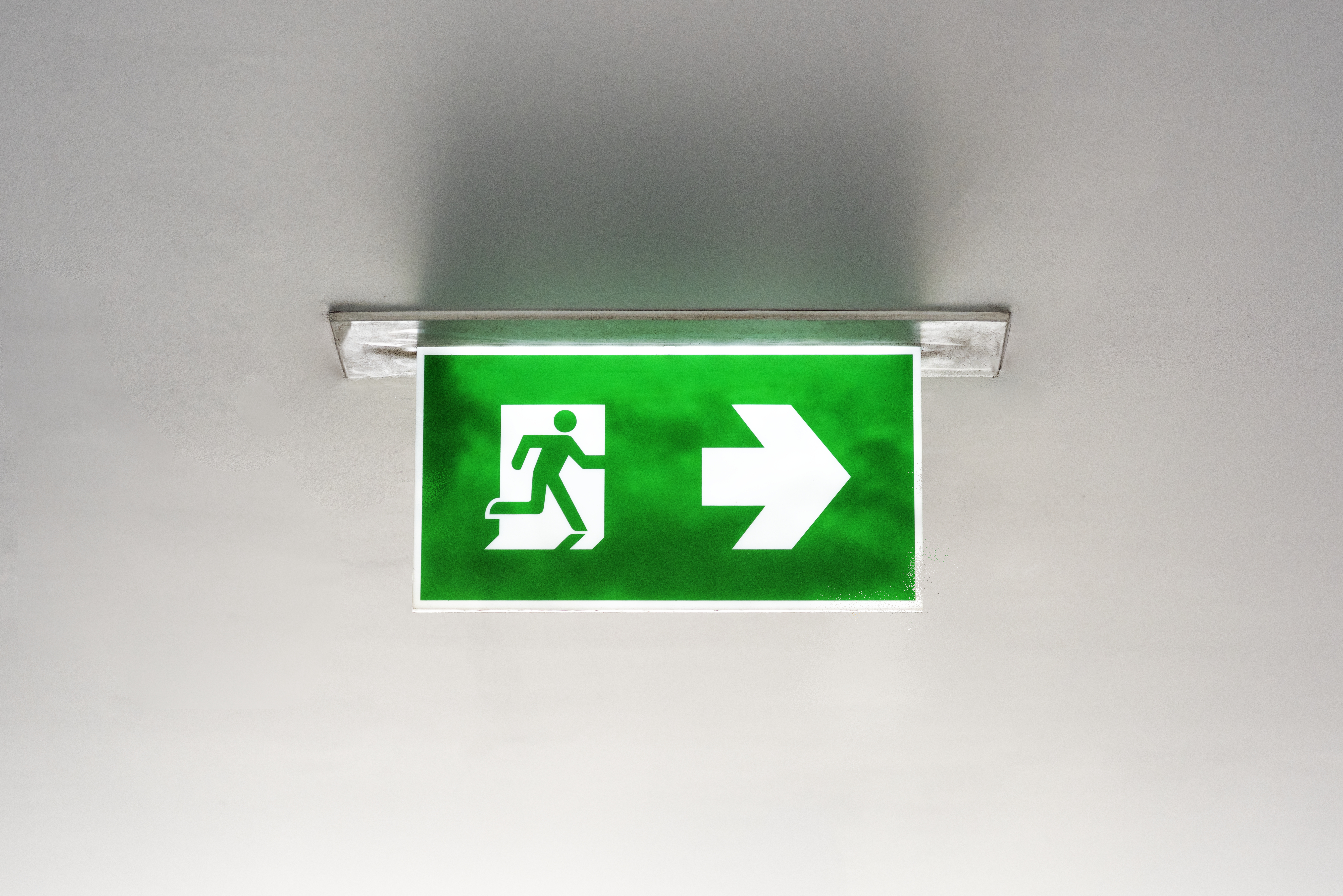 Green emergency fire exit sign hanging from ceiling