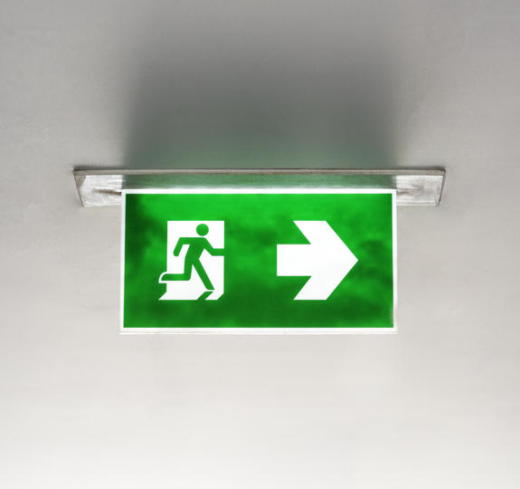 Green emergency fire exit sign hanging from ceiling