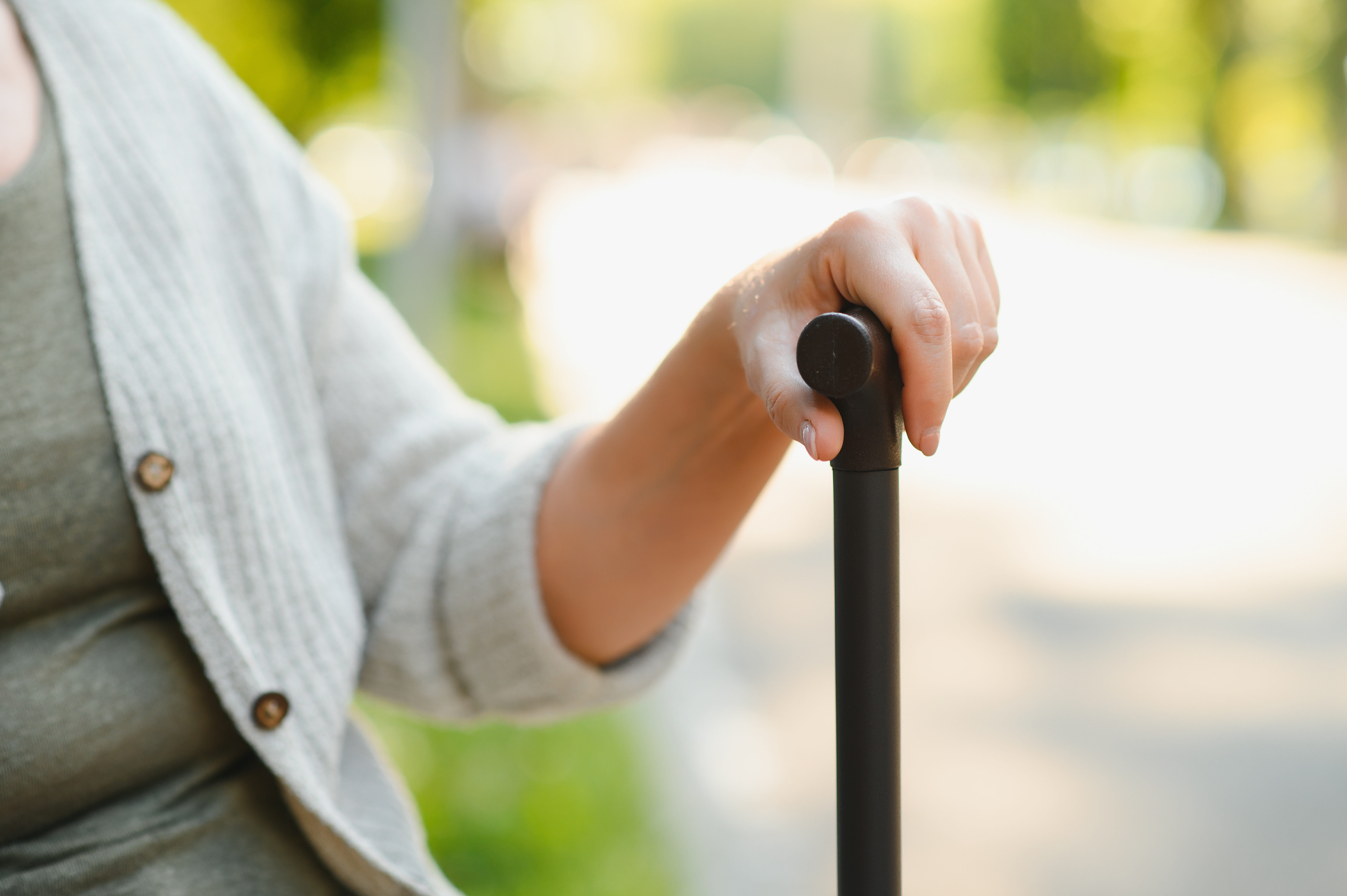 Close up photo of an elderly woman's hand resting on the handle of her walking stick