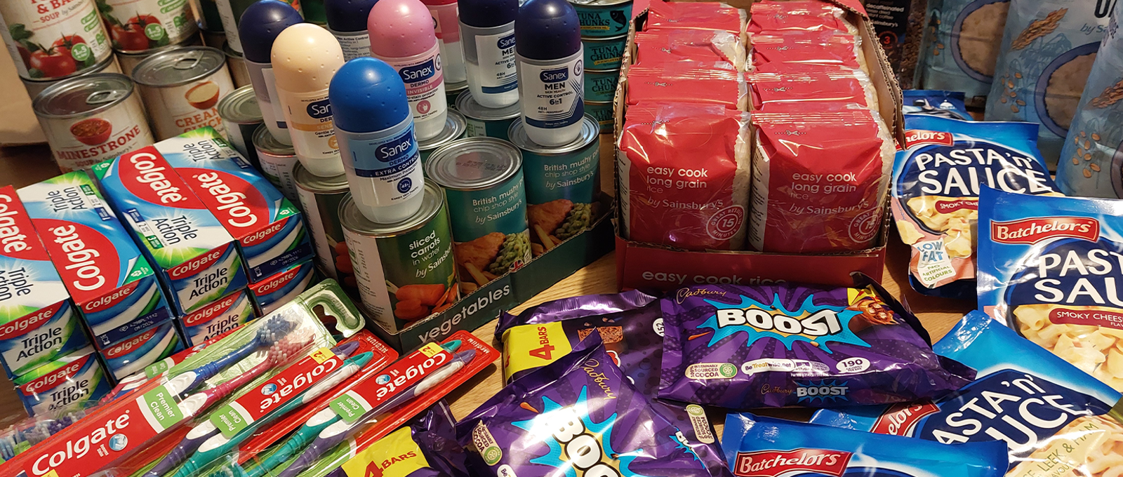 Photo of a table full of food and toiletries items, tins, chocolate, toothpaste etc