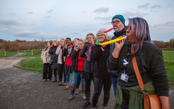 Group of people outside with party blowers in their mouths