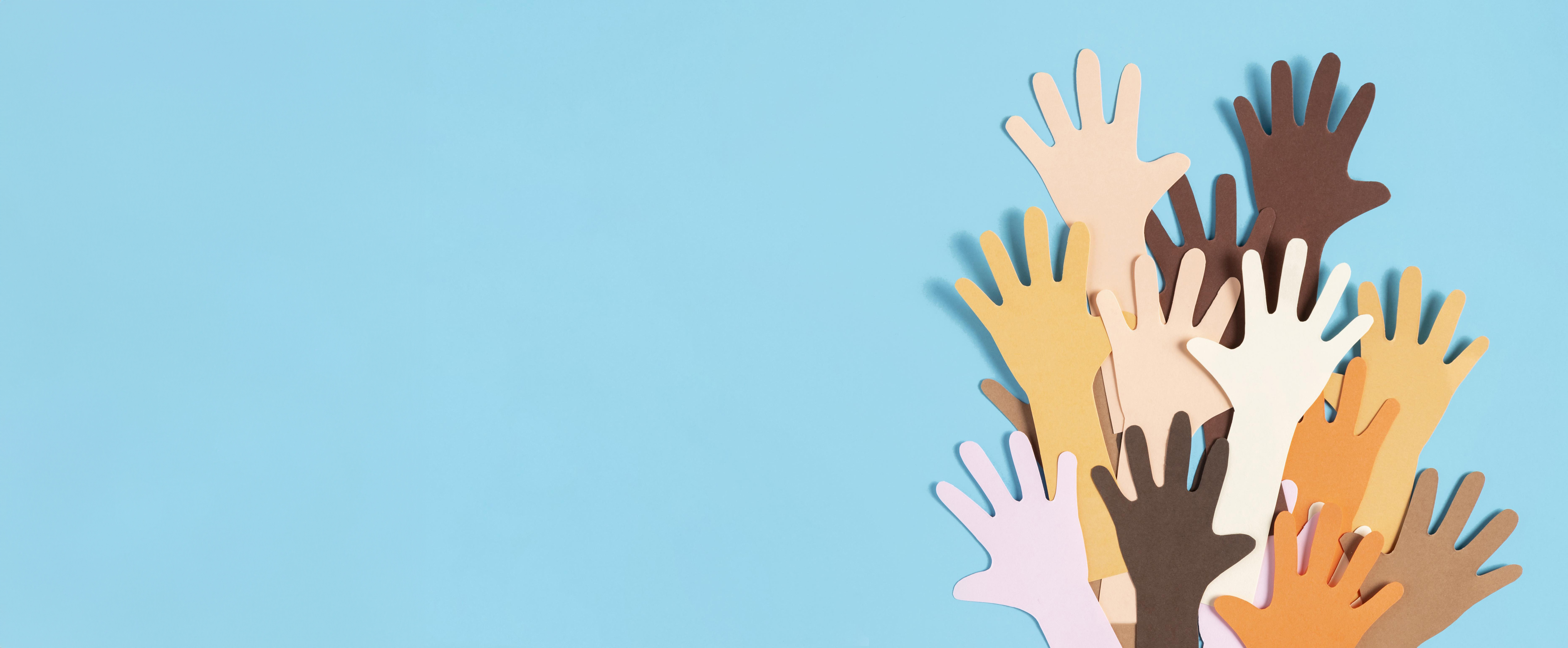 Various hands made of paper cutouts of different sizes and colours illustrating diversity