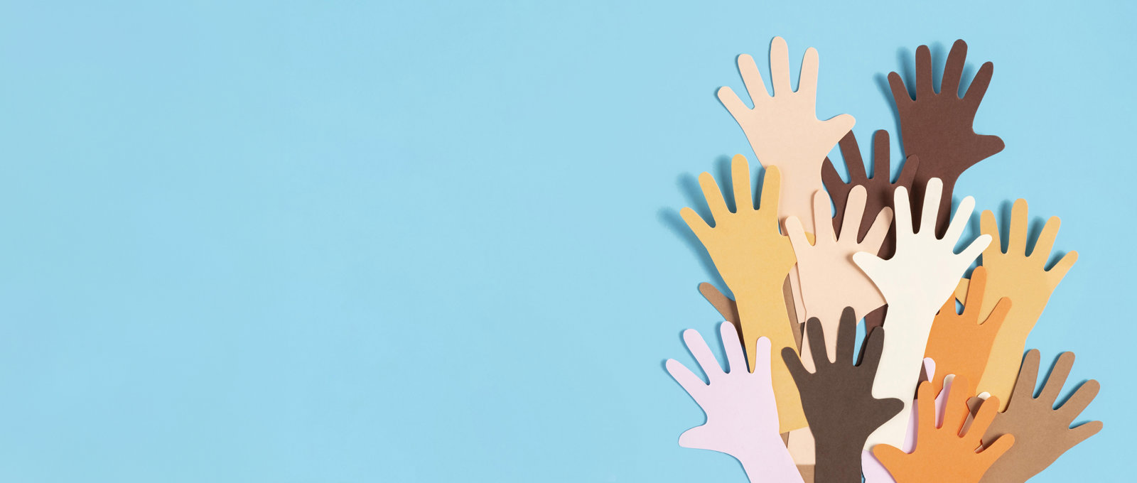 Various hands made of paper cutouts of different sizes and colours illustrating diversity