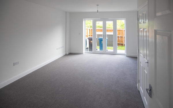 Photo of a plain white living room with french doors looking into garden